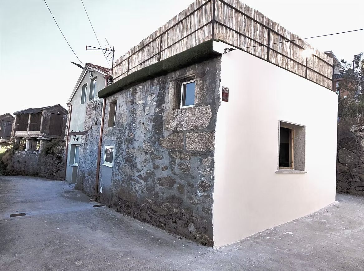 Fachada de Casa Cosmeiro, de granito y cal, junto a los hórreos