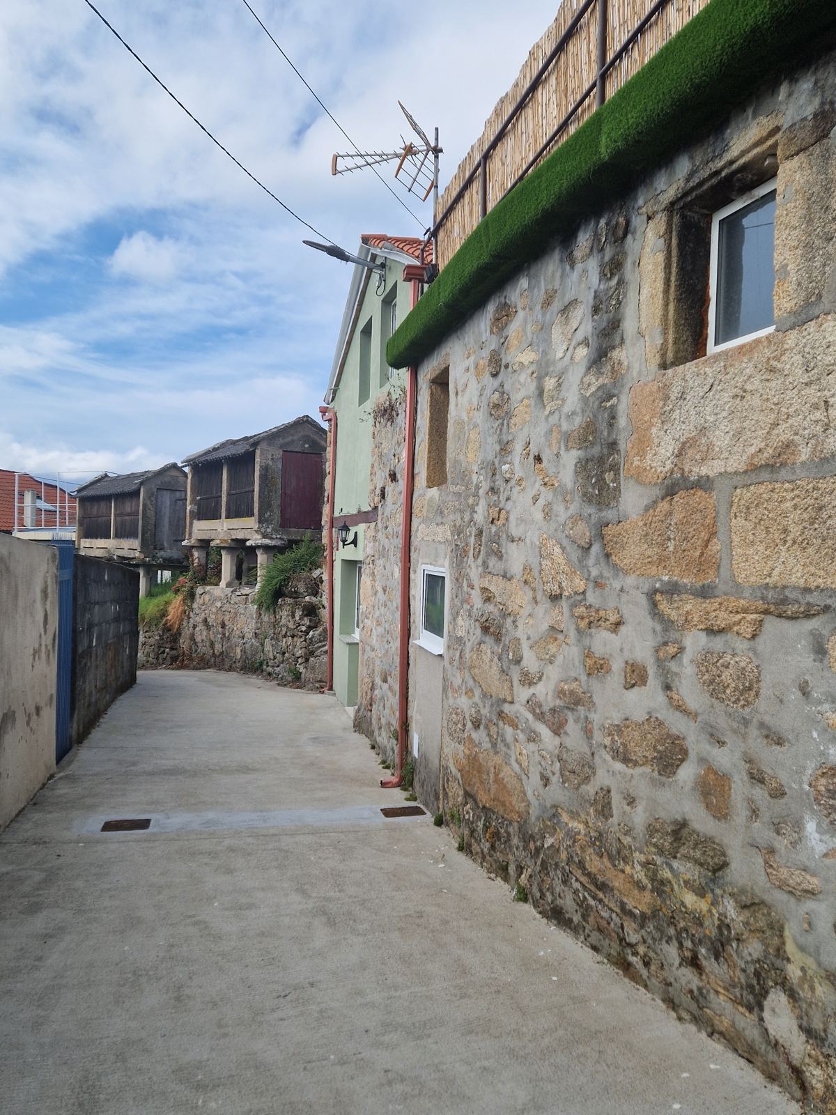 Fachada de granito en una calle con hórreos