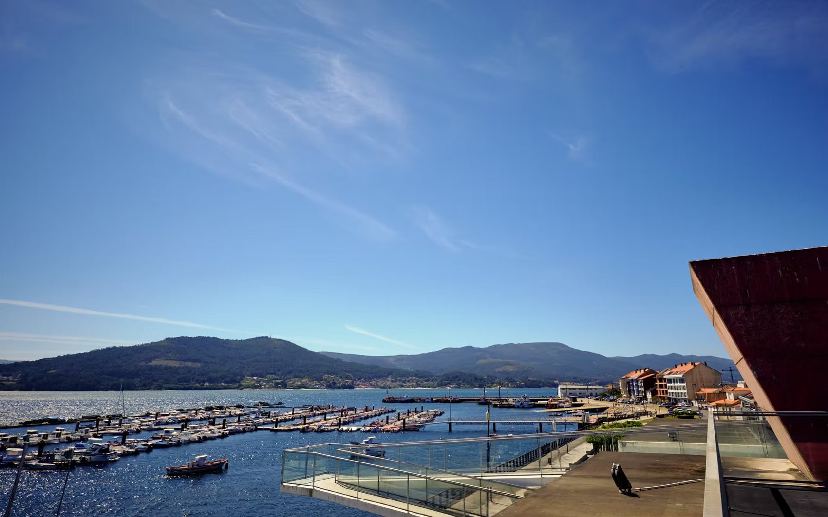 Puerto deportivo con barcas en la ría y los montes al fondo