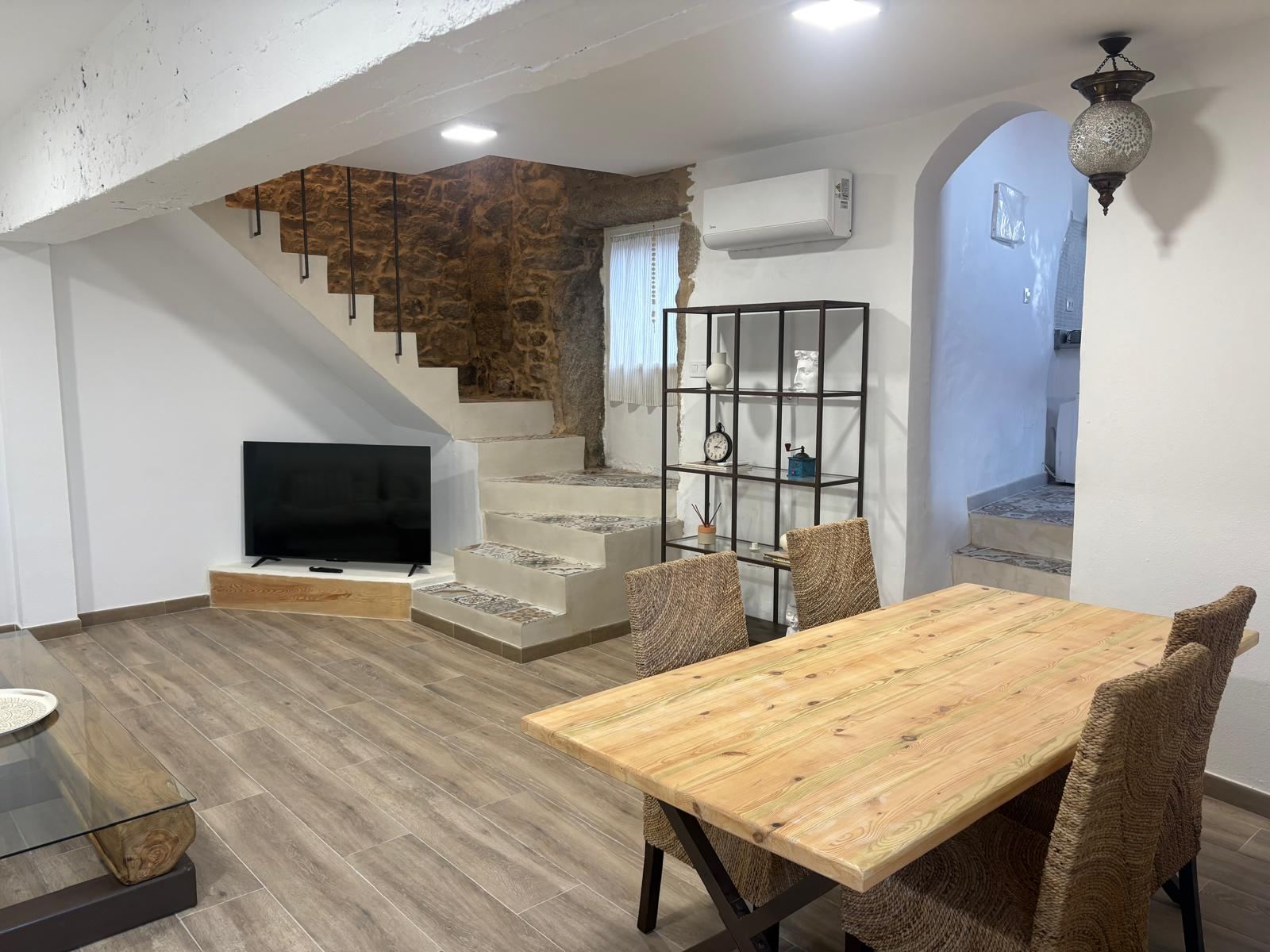 Salón comedor de Casa Cosmeiro con escalera de piedra y mesa de madera