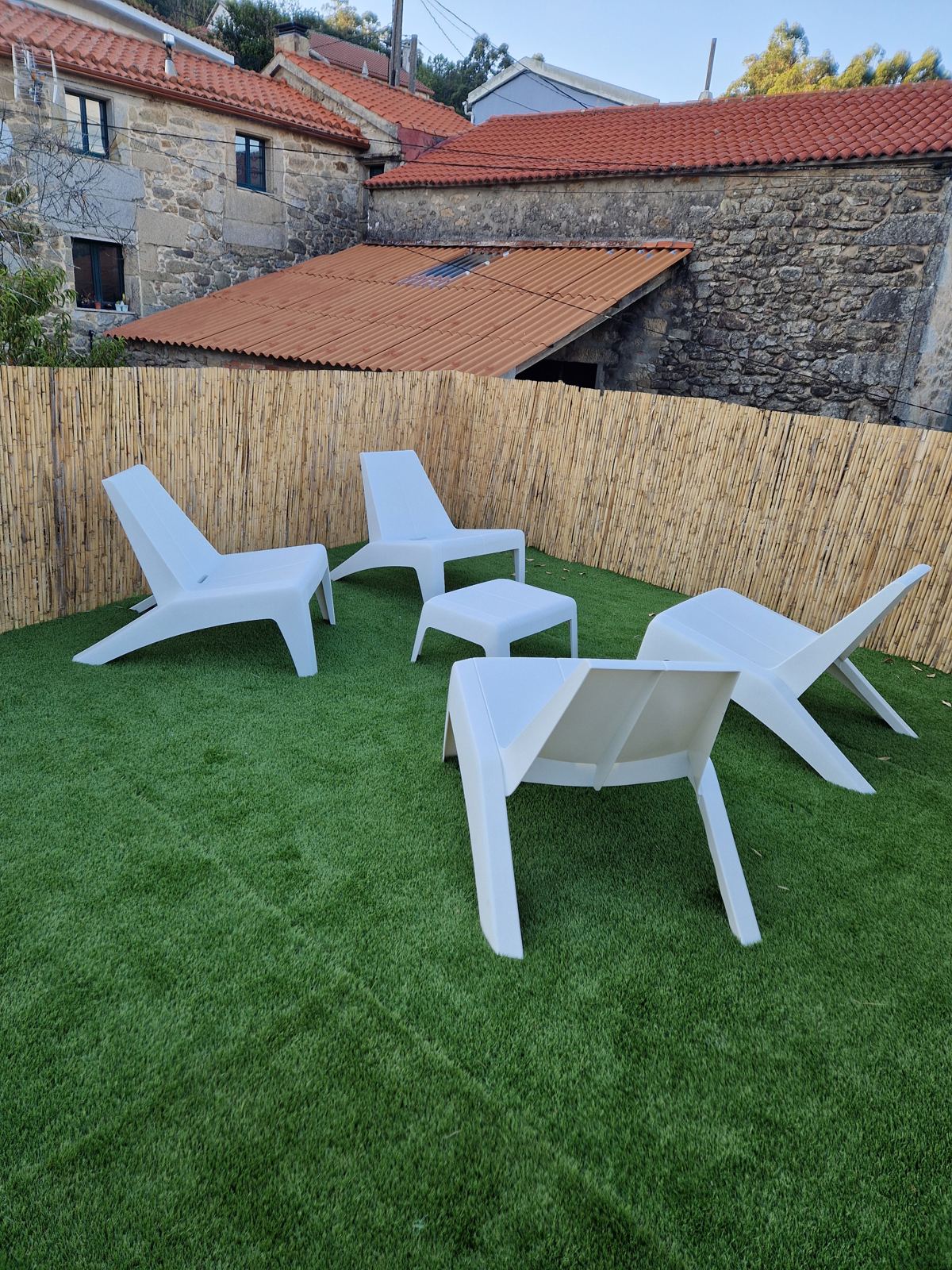 Terraza con césped y cuatro tumbonas